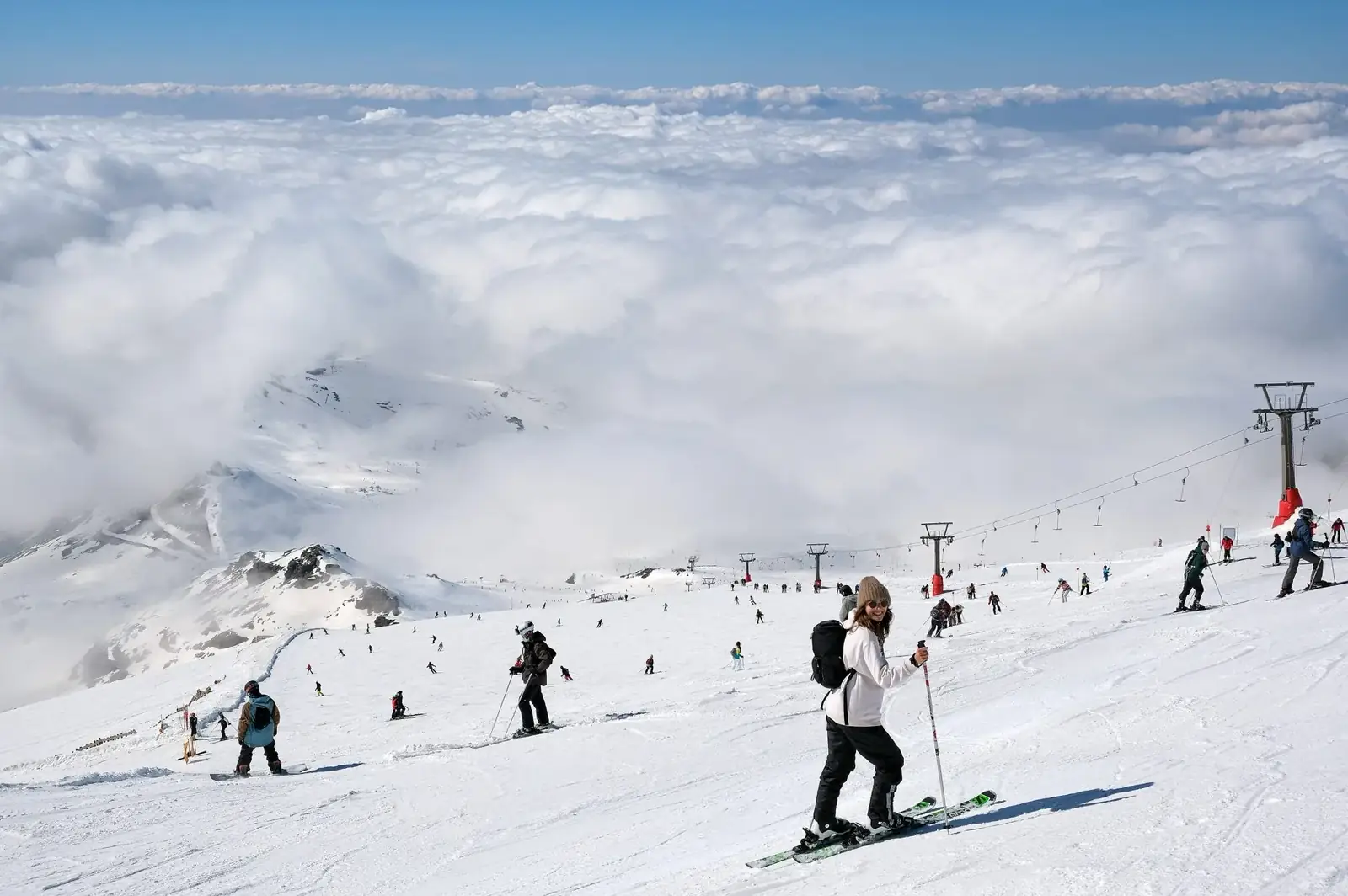 Skiers on a groomed piste above the clouds at the Sierra Nevada ski resort near Granada